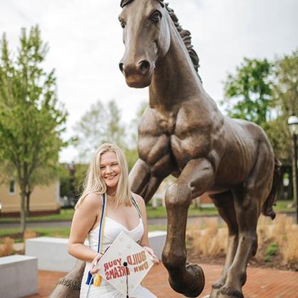 Bradyn Van Sant ’22 in front of the horse statue on campus.